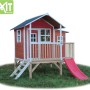 Rotes EXIT Loft 350 Holzspielhaus mit Rutsche, Treppe und Anbau im Garten.