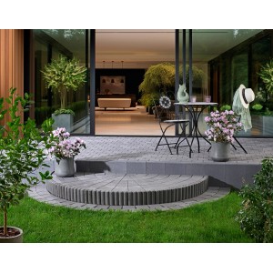 Verlegtes Kann Pflaster Casalina, 14x14x6 cm, Vulkananthrazit, mit Sitzgruppe und Bepflanzung im Garten.