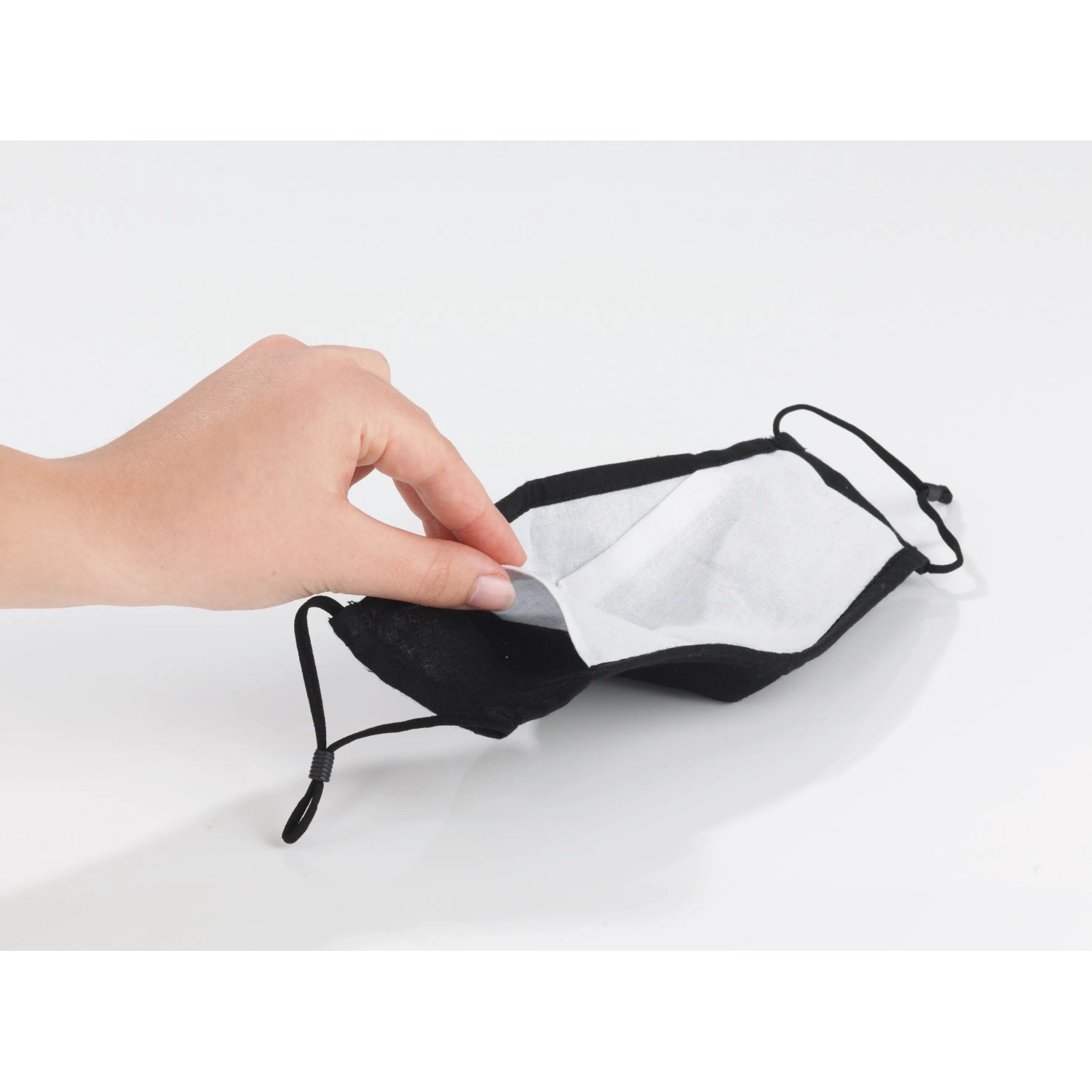Mund-Nasen-Schutz aus Baumwolle: Einlegen eines Filters in eine schwarze Stoffmaske.