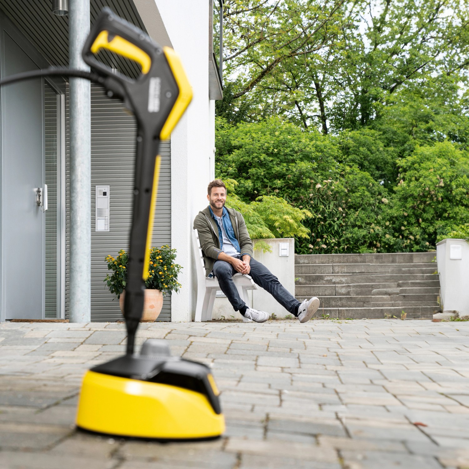 Kärcher Flächenreiniger T 5 T-Racer im Einsatz vor Hausfassade. Der Nutzer macht eine Pause.