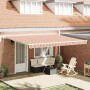 Gestreifte, einziehbare Markise in Orange-Weiß über einer Terrasse mit Möbeln am Ziegelhaus.