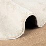 Beiger vidaXL Oviedo Kurzflor Teppich, aufgerollt auf Holzboden. Zeigt weiche Textur und den runden Rand.