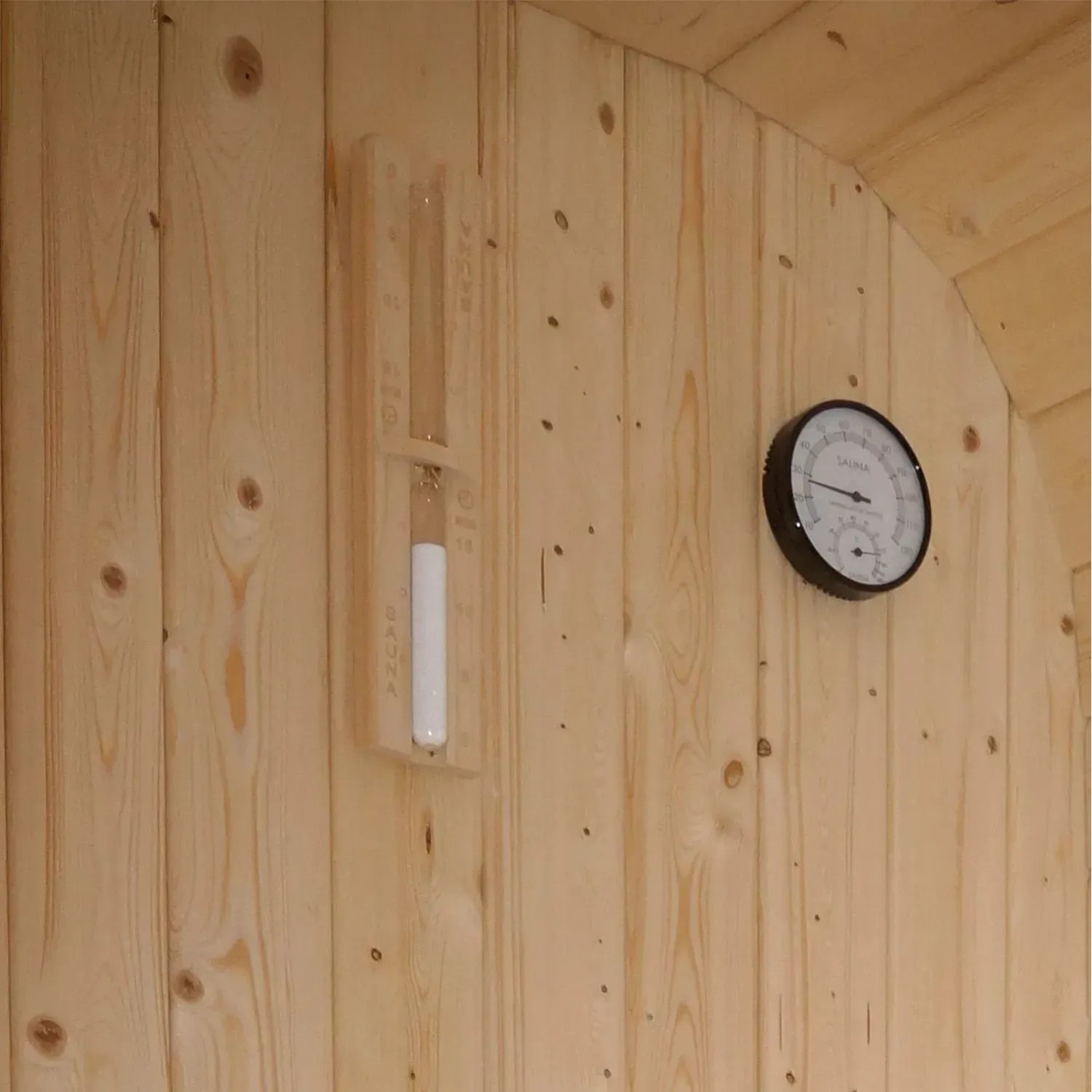 Innenansicht Artsauna Cube Fasssauna Fjora mit Thermometer und Sanduhr an Fichtenholz Wand.