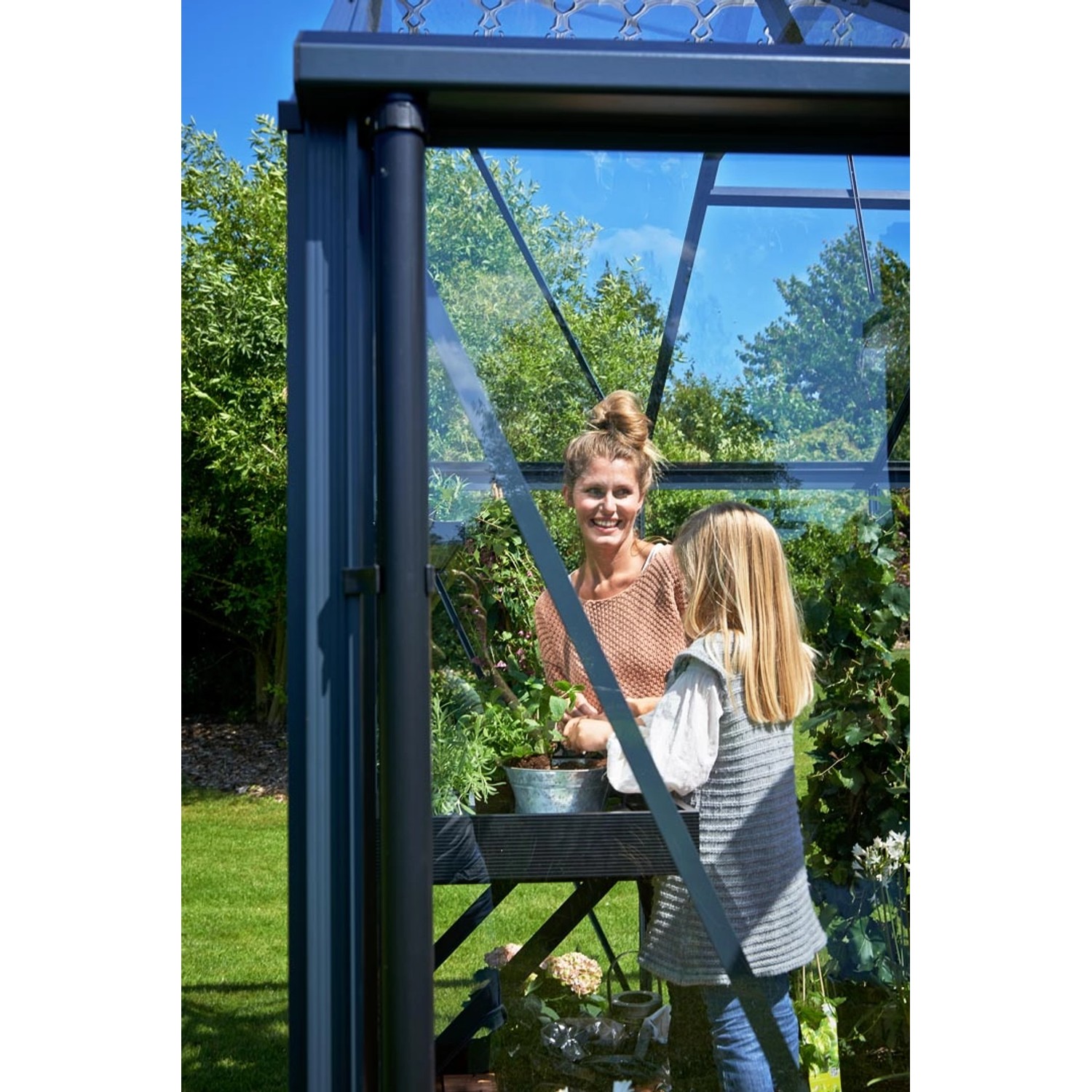 Juliana Gewächshaus Orangerie 15, schwarz-anthrazit, mit Mutter und Tochter beim Gärtnern.