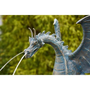 Detailaufnahme der bronzefarbenen Rottenecker Drachenvogel-Skulptur mit Wasserspiel im Gartenteich.