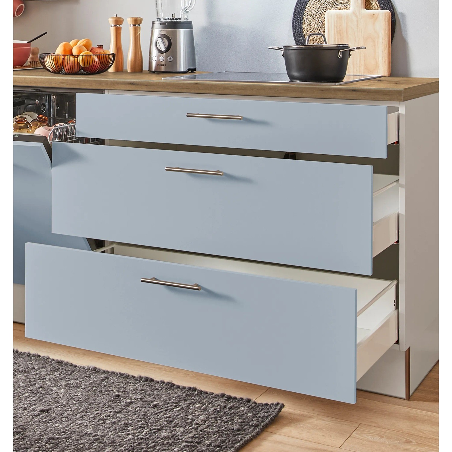 Küchenzeile in Pastellblau mit offenen Schubladen und Edelstahlgriffen. Einbauküche mit viel Stauraum.