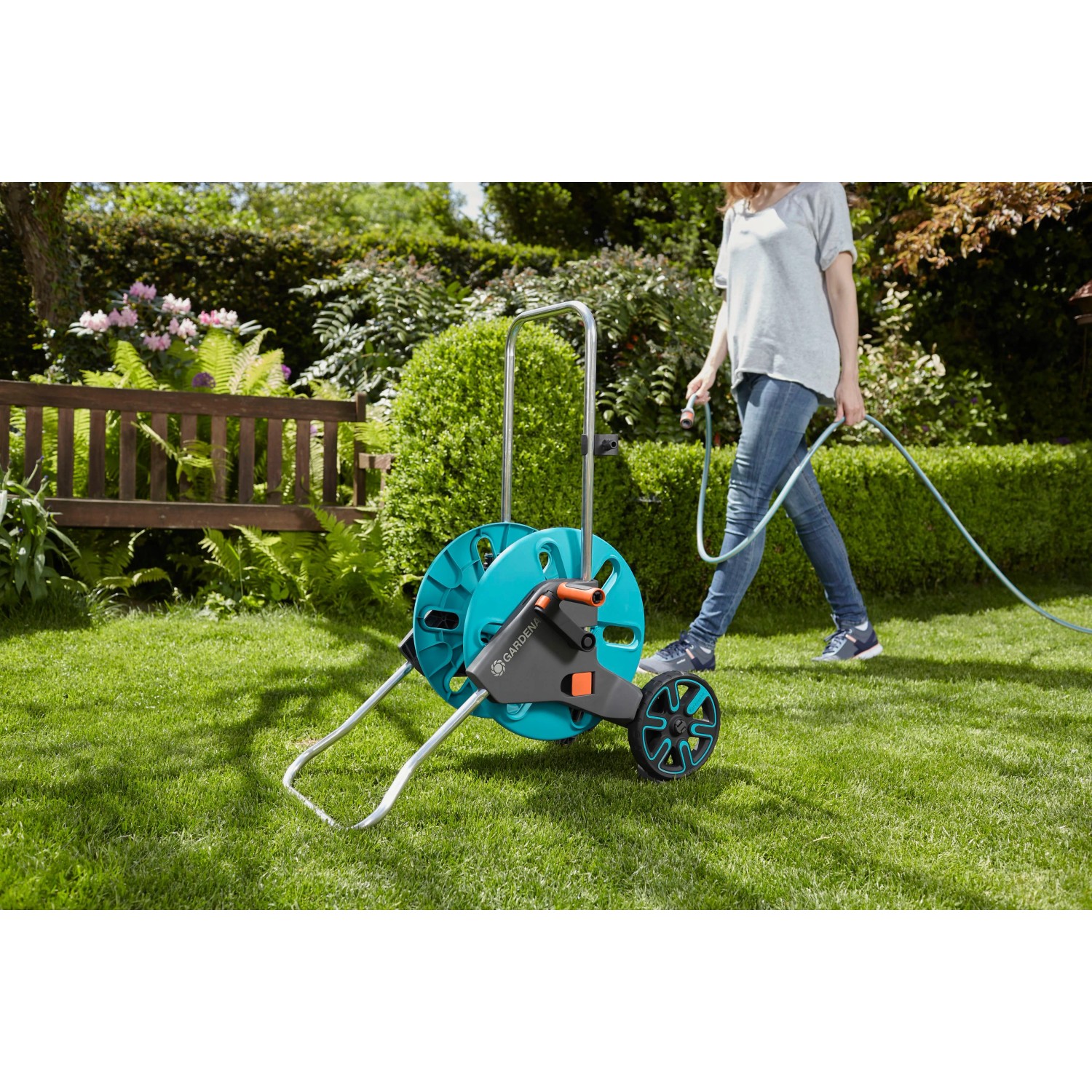 Gardena CleverRoll M Schlauchwagen im Garten mit Frau beim Bewässern.
