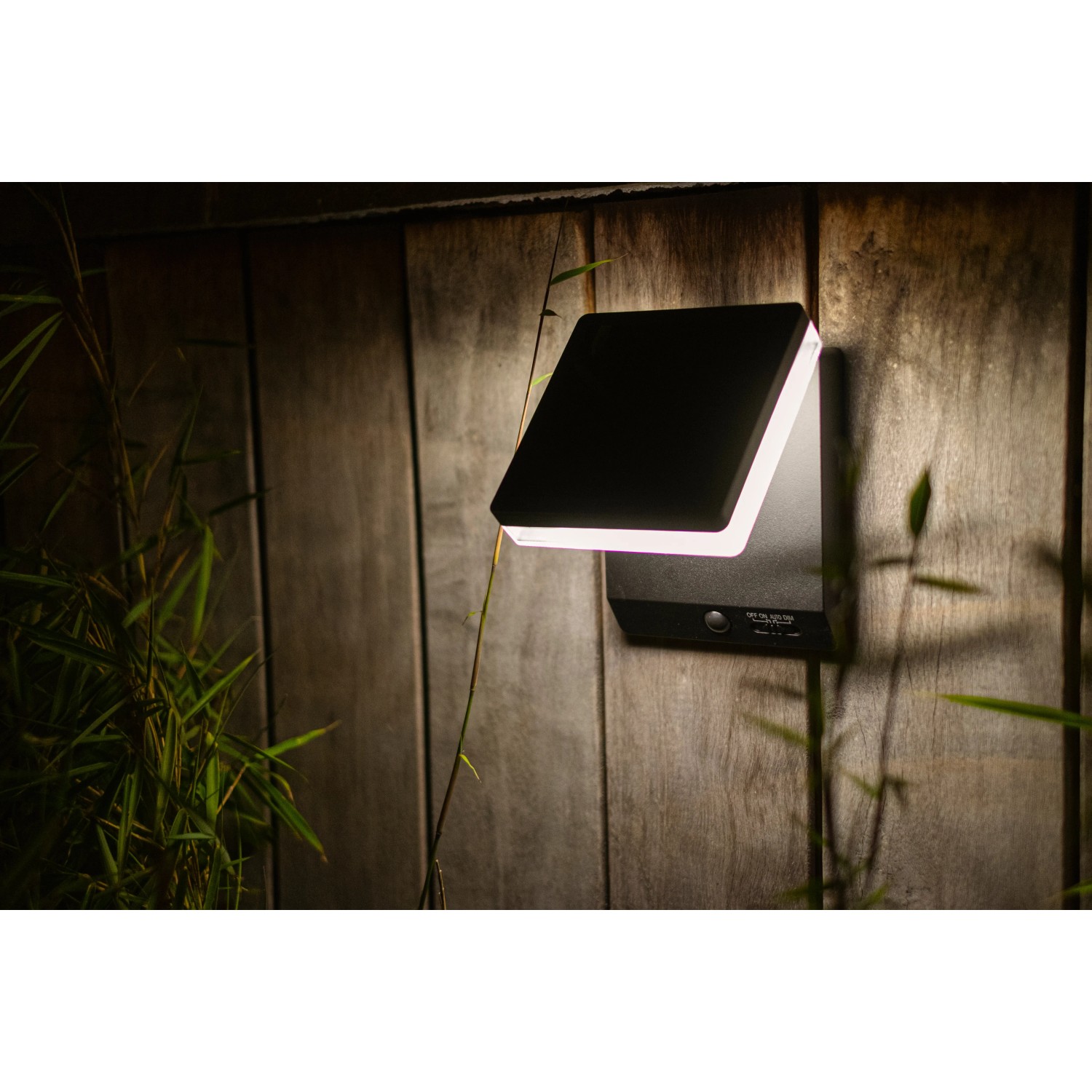 Moderne, eckige Lutec Solar-LED-Außenleuchte Moze in Schwarz Matt an einer Holzwand.