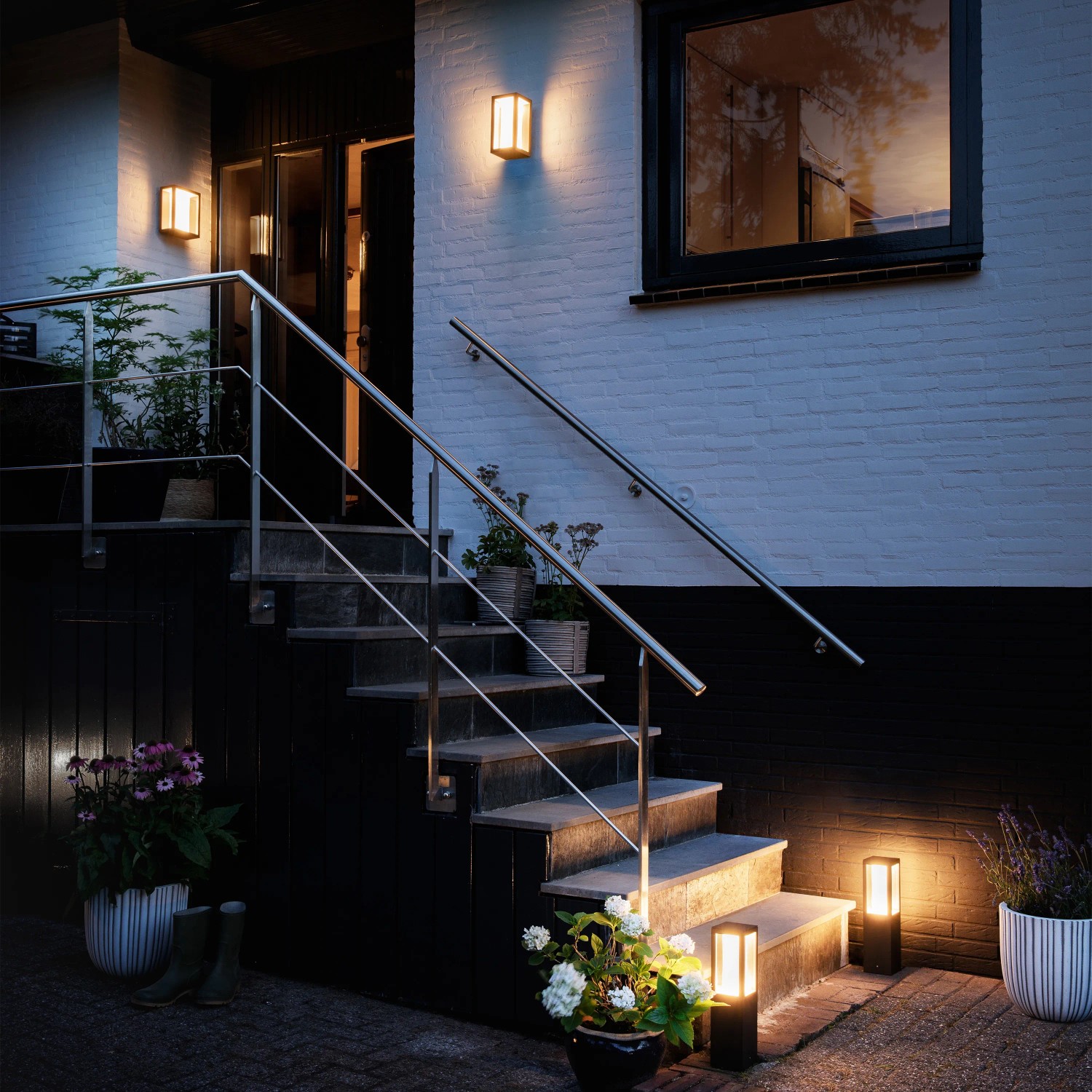 Beleuchteter Hauseingang mit Philips Hue LED-Wandleuchte Impress in Schwarz und Wegeleuchten.