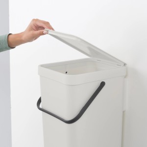 Brabantia Abfallbehälter Sort & Go, 16 l, Grau, mit geöffnetem Deckel an der Wand montiert.
