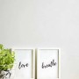 Uni Tapete in Weiß mit zwei Bilderrahmen mit den Schriftzügen 'Love' und 'Breathe'.