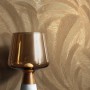 Goldene Vliestapete mit strukturierten Palmenblättern und Glanz. Dekorative Natur-Tapete für Wohnräume.