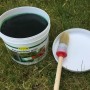 Eimer Schacht Raupenleim Grün 500g mit Pinsel und Deckel auf Rasen für biologische Schädlingsbekämpfung.