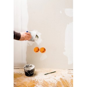 Handwerker spachtelt Wand mit Japanspachtel-Set von LUX. Werkzeug und Spachtelmasse im Einsatz.