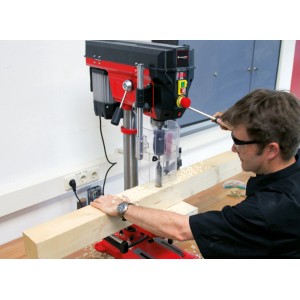 Einhell Säulenbohrmaschine TE-BD 750 E beim Bohren in Holz, rote Tischbohrmaschine mit Mann.