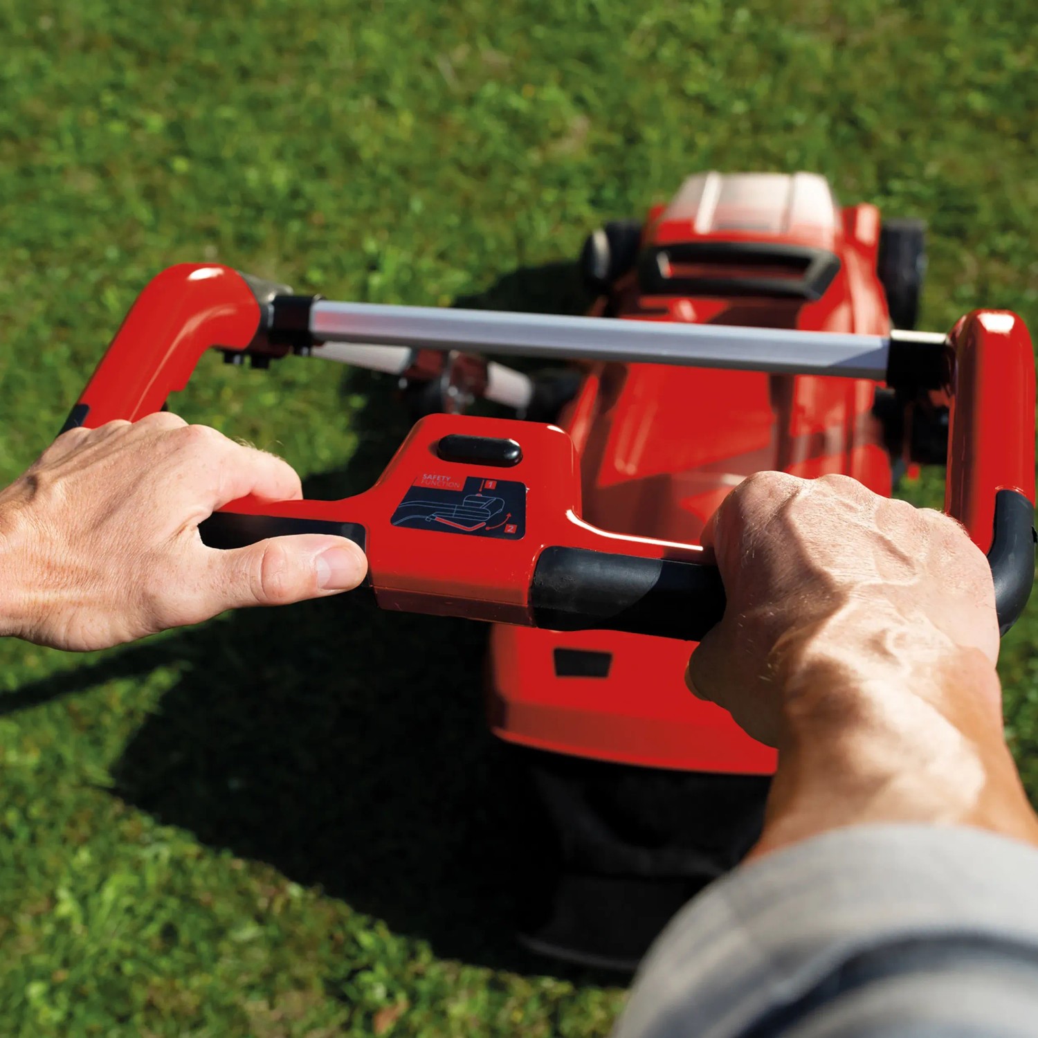 Einhell Akku-Rasenmäher GE-CM 36/37 Li Solo in Nutzung, rotes Gehäuse, Holm in Händen.