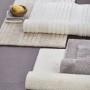 Verschiedene Schöner Wohnen Badteppiche Bahamas in Weiß-, Beige- und Grautönen, gerollt und flach liegend.