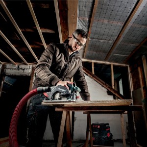 Handwerker sägt mit Metabo Akku-Handkreissäge KS 18 LTX 57 ein Brett. Inkl. Staubsaugeranschluss.