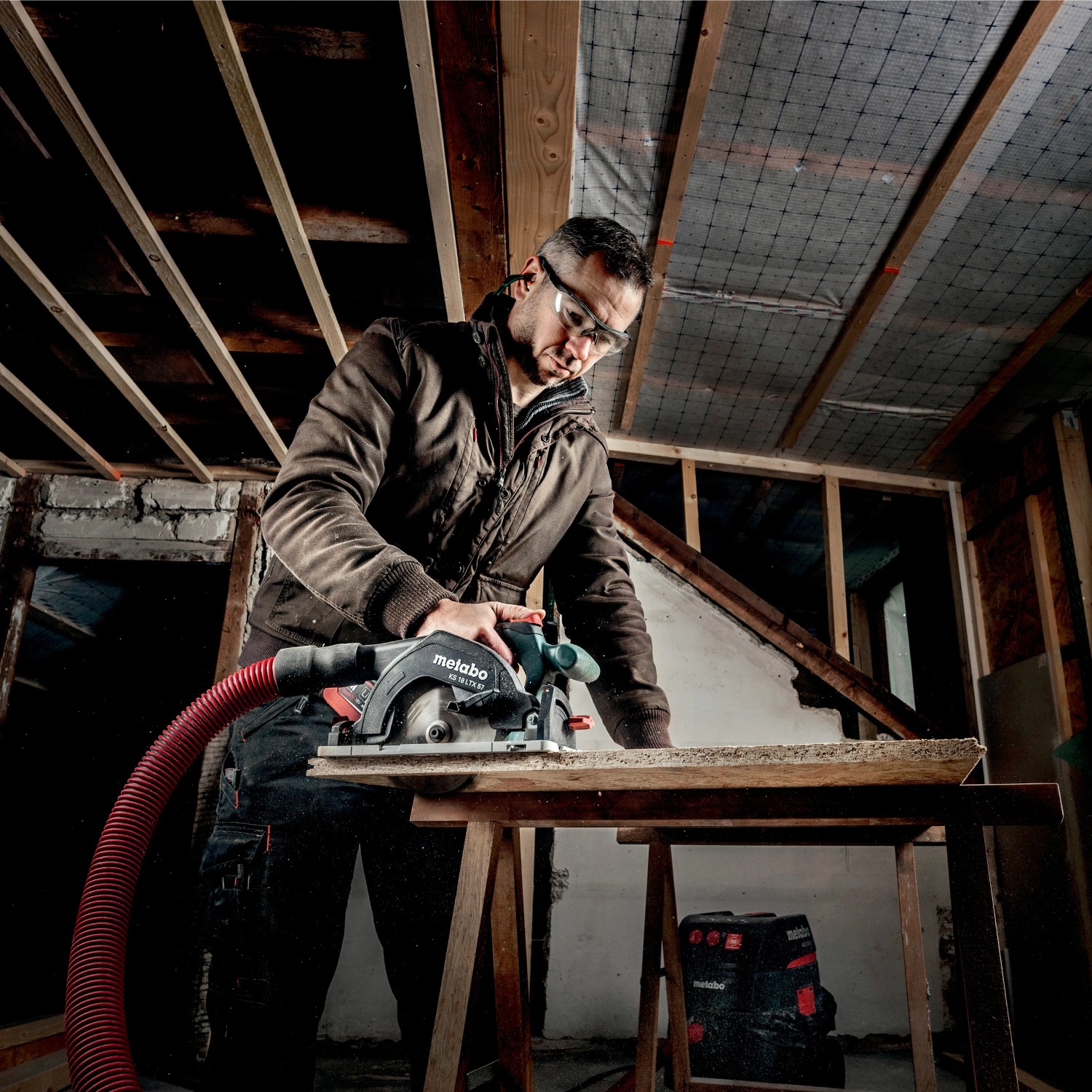Handwerker sägt mit Metabo Akku-Handkreissäge KS 18 LTX 57 ein Brett. Inkl. Staubsaugeranschluss.