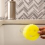 Scrub Daddy Caddy: Gelber Schwamm mit Gesicht im Spülbecken-Halter mit Saugnapf.