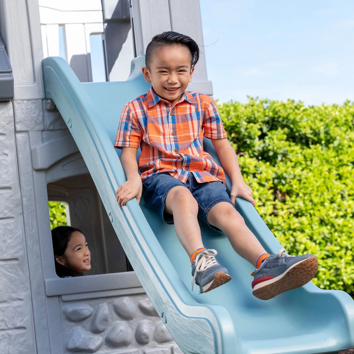 Kind rutscht auf der Rutsche des Step2 Spielhaus Adventures 2-Etagen hinunter.