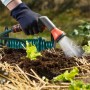 Gartenbewässerung: Hand gießt mit Sprühdüse junge Salatpflanzen. Grüner Schlauch im Hintergrund.