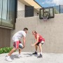 SPORTNOW Basketballkorb, schwarz, an Betonwand montiert. Zwei Männer spielen Basketball im Garten.