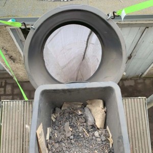 Flexible Scorprotect Bauschuttrutsche mit Einfülltrichter leitet Schutt in einen Baueimer. Ideal für Abbrucharbeiten.