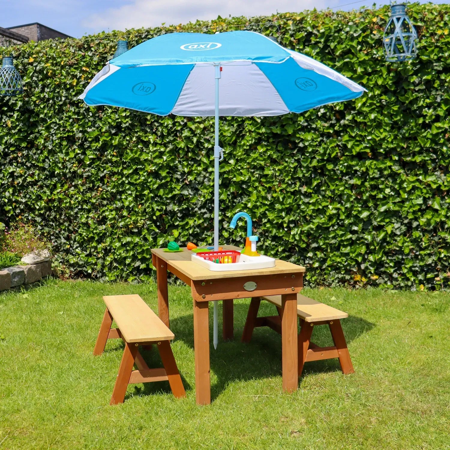 Axi Picknicktisch Dennis mit Sonnenschirm, Spielküche und Zubehör im Garten.