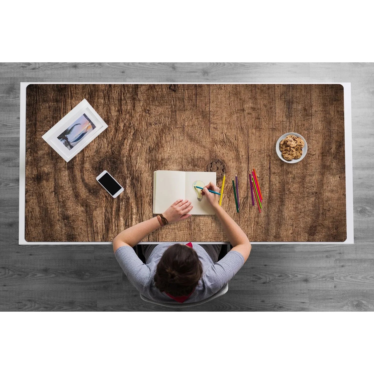 Braune Schreibtischunterlage in Altholz-Optik, 100x50 cm. Eine Person zeichnet darauf, ideal für Büro & Arbeitsplatz.