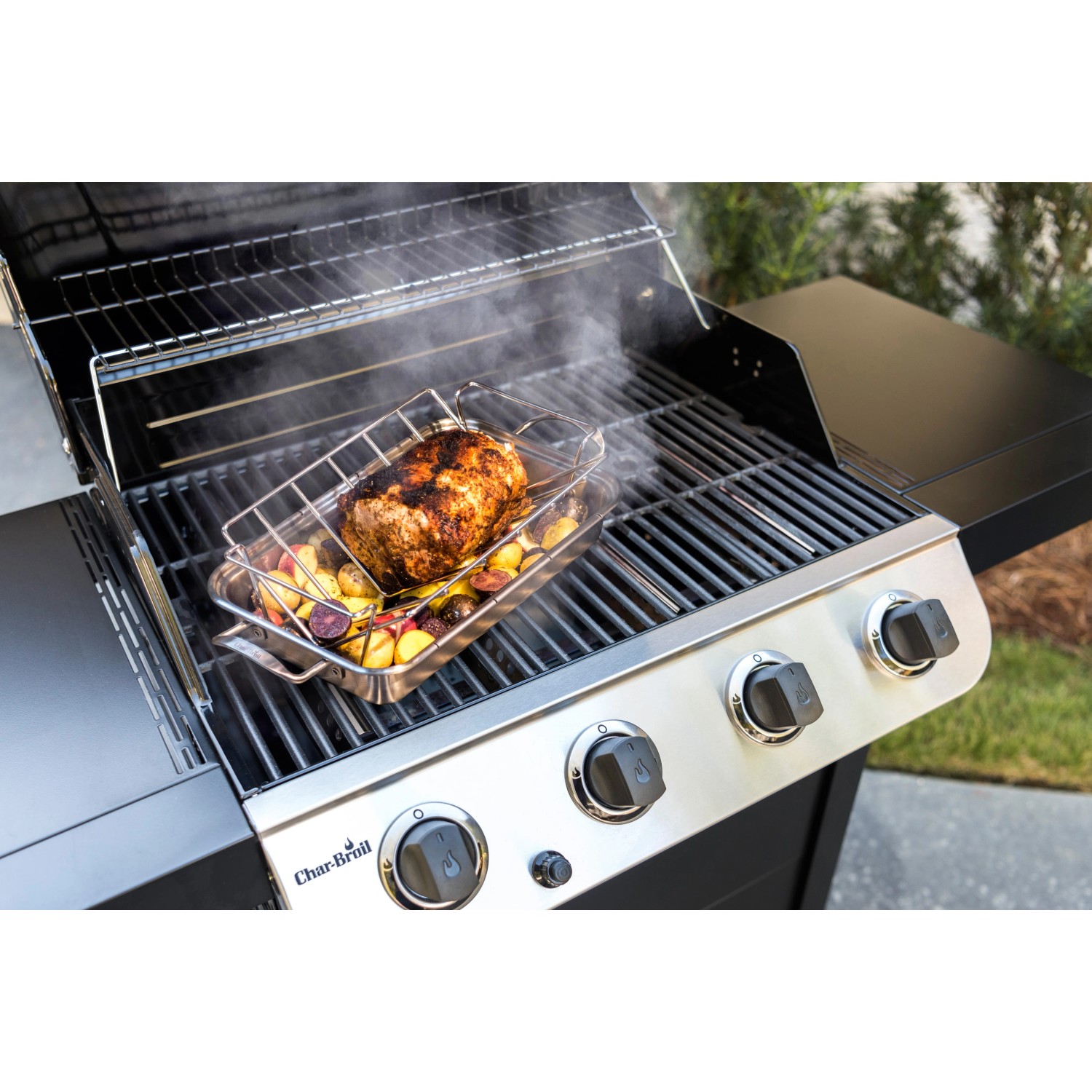 Char-Broil Grill+ Rippen- und Bratenhalter mit Braten und Kartoffeln auf einem Grill.