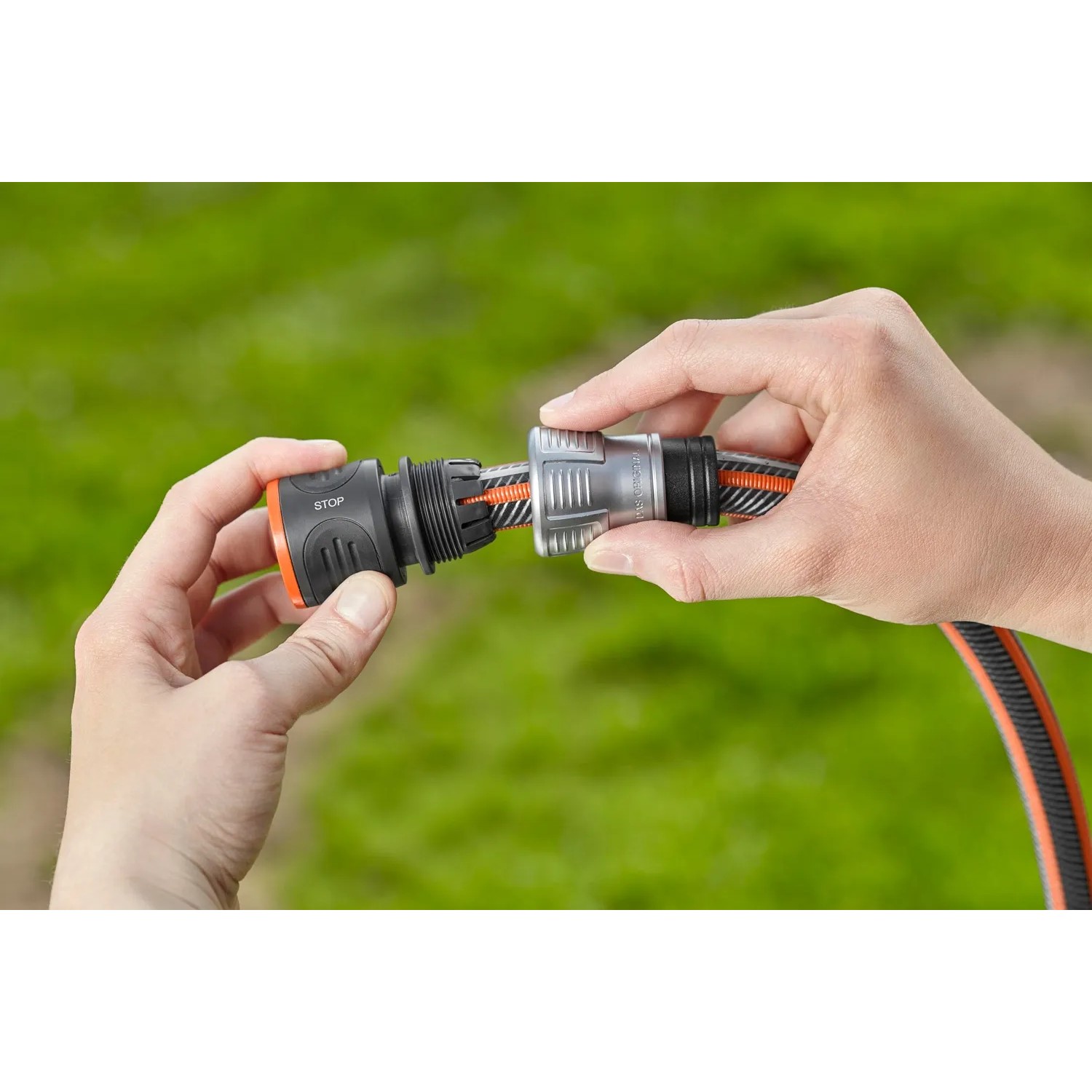 Hände verbinden Gardena Premium Schlauchverbinder mit Wasserstop an Gartenschlauch.