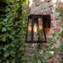 Lutec Fia LED Solar-Wandleuchte, anthrazitfarben, an Backsteinwand mit Efeu.
