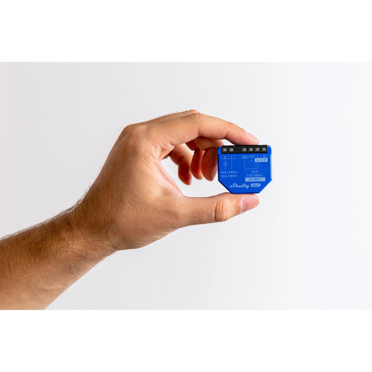 Hand hält blaues Shelly Relaismodul 1 Gen3 für Hausautomation.