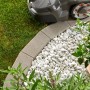 Graue Kann Mähkante Vigneto als Rasenkante mit Mähroboter und weißen Ziersteinen im Garten.