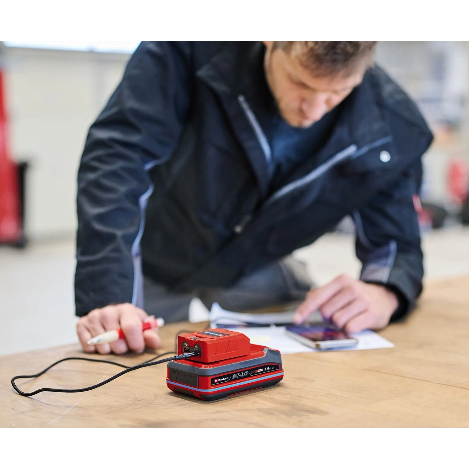 Einhell USB-Akku-Adapter TC-CP 18 Li USB A/C-Solo mit Akku und Smartphone beim Laden.