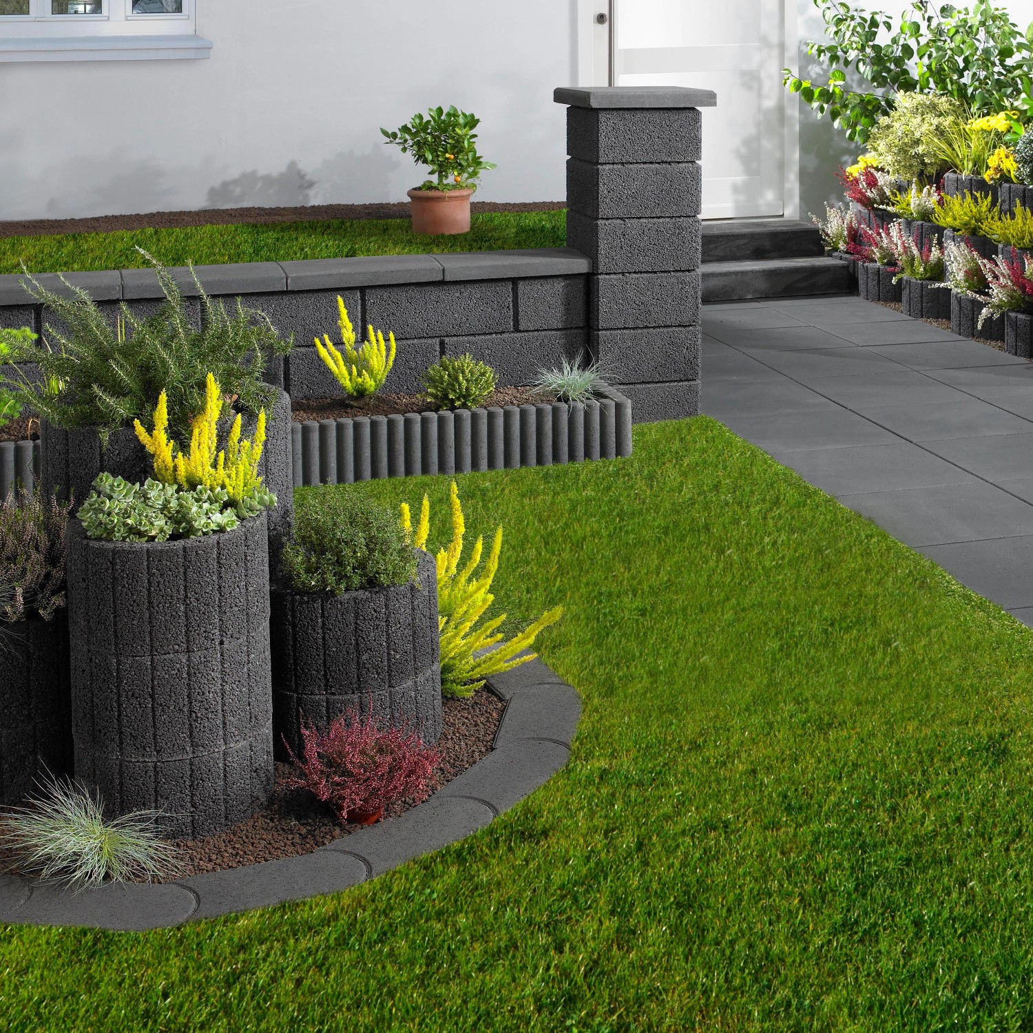 Anthrazit Gartenmauer aus Beton mit Bepflanzung als Grundstückseinfassung.