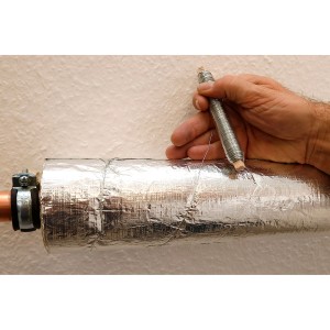 Hand befestigt silberne Rohrisolierung an Kupferrohr mit verzinktem Bindedraht von Spule. Für Heizungs-Installation.