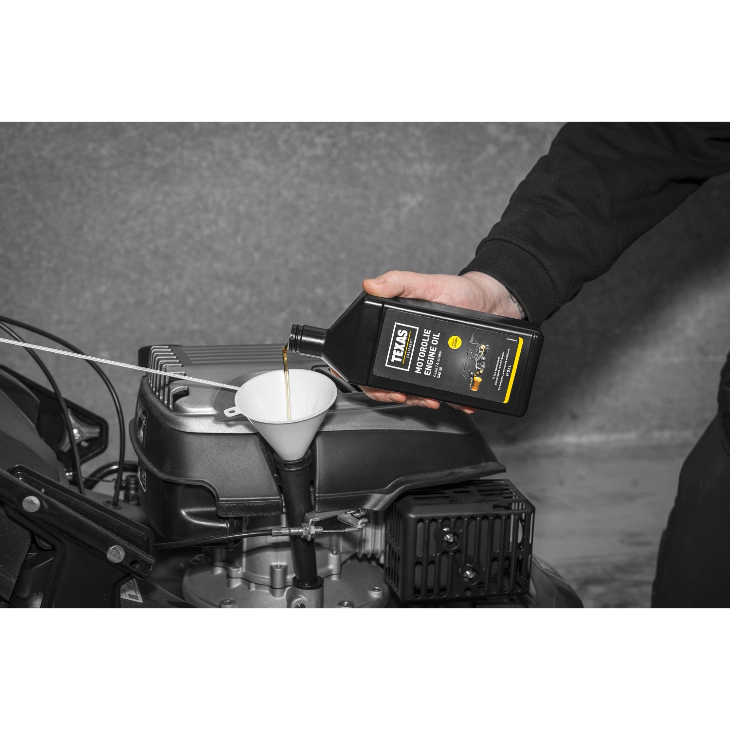 Texas Motoröl SAE30 0,6 l wird in einen Rasenmäher eingefüllt.