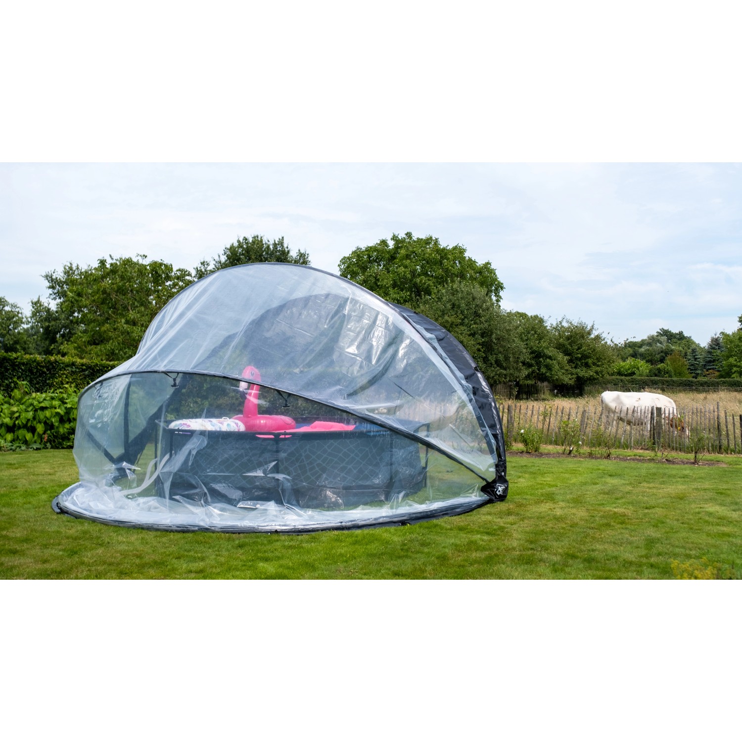 Exit Poolabdeckung ECO Ø 550 cm auf Rasen, transparente Kuppel schützt Pool mit Flamingo.