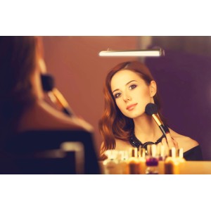 Frau schminkt sich unter Müller-Licht LED-Badleuchte Belle Lux Weiß.