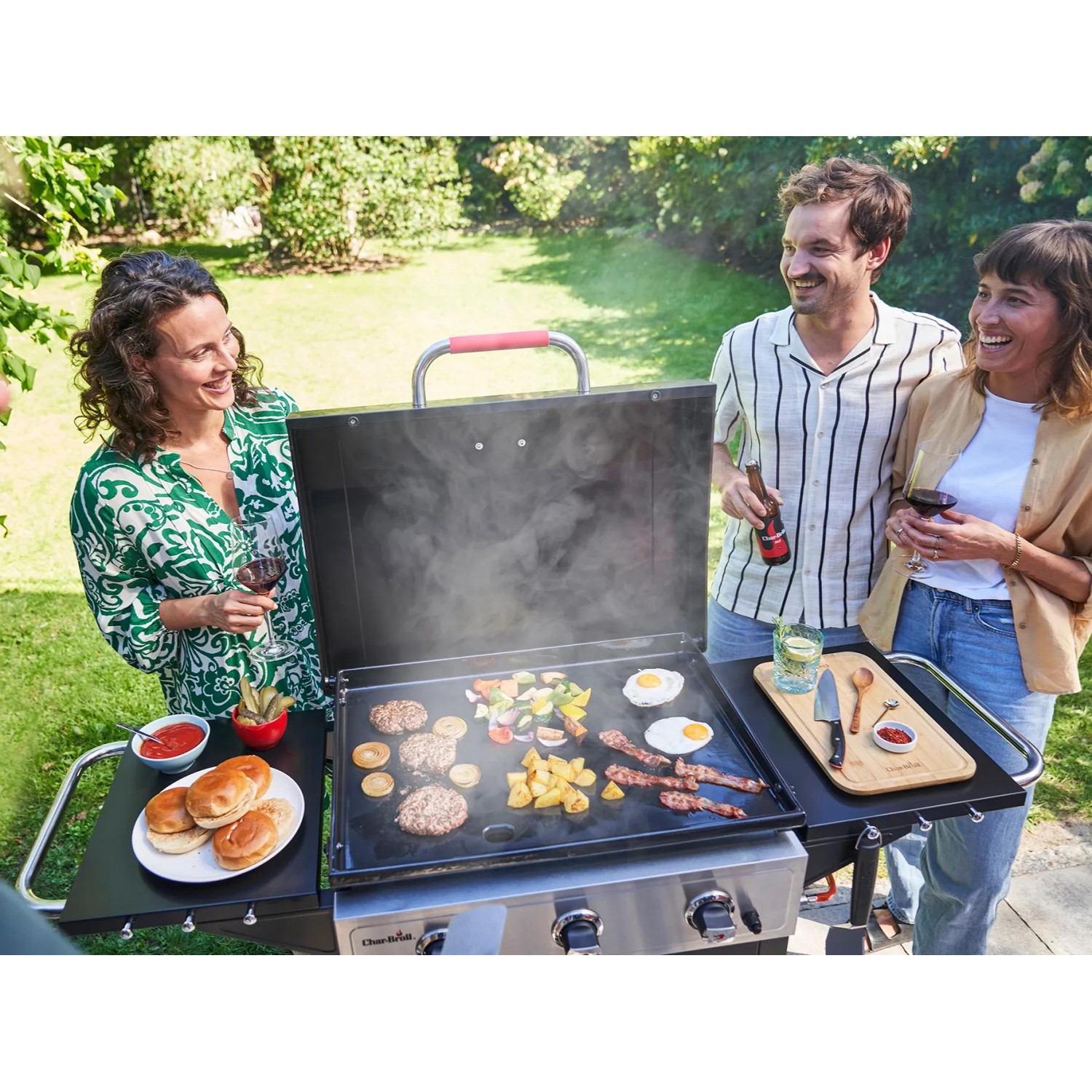 Char-Broil Griddle 3400 Gasgrill mit Gusseisenplatte beim Grillen mit Freunden im Garten.