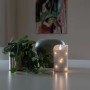 Weiße Konstsmide LED Echtwachskerze mit 3D-Flamme, Timer und silbernem Draht auf Tisch.