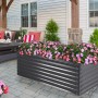 Floraworld Pflanzkasten Welle, anthrazit, 150x60x60 cm, bepflanzt mit rosa Blumen.