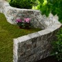 Geschwungene Mauer aus Vigneto Jura-Nuanciert Mauersteinen im Garten.