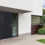 Anthrazitgraue Vente-unique Agueda Haustür aus Stahl, links angeschlagen, an modernem Haus mit Glas.