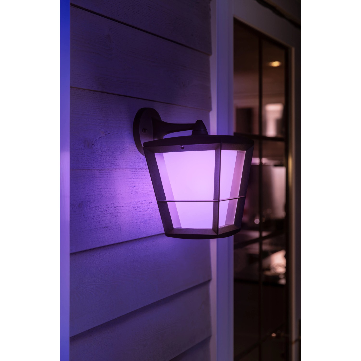 Hängende Philips Hue Econic LED-Laterne in Schwarz mit violetter Beleuchtung an Hauswand.