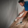Mann verlegt Laminat mit wolfcraft Einpass-Set für Laminat und Designboden.