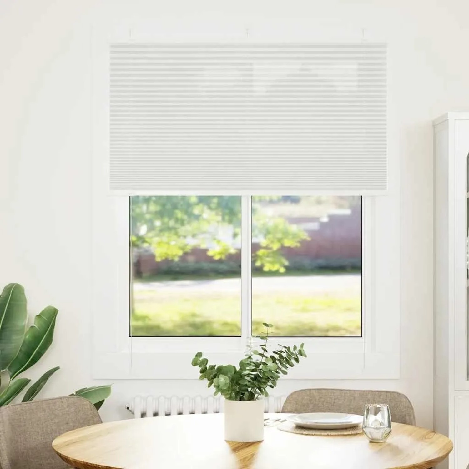 Hellgraues Plissee aus Polyester am Fenster, bietet Sichtschutz. Modernes Faltrollo für Wohnzimmer & Büro.