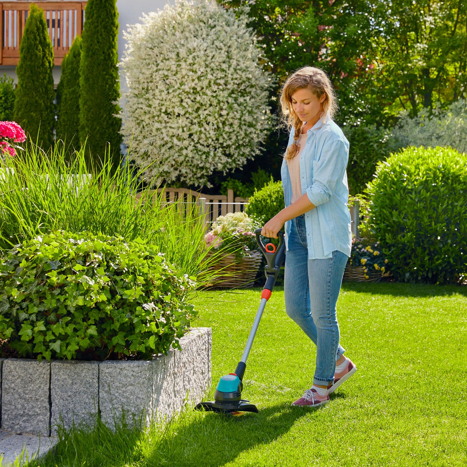 Frau trimmt Rasen mit Gardena Akku-Trimmer EasyCut 23/18V. Inkl. Akku-Set.